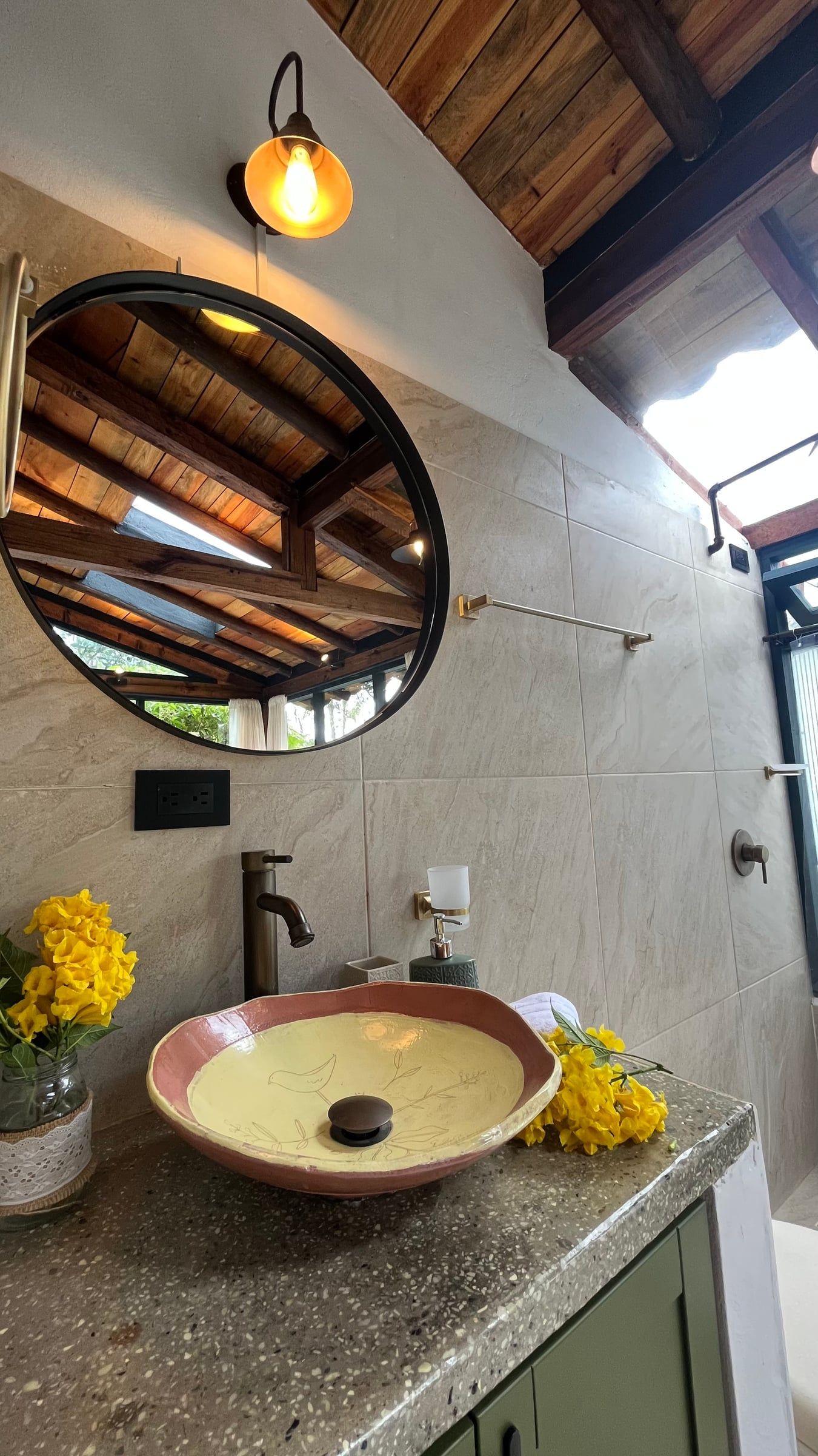 Detalle del baño con lavamanos de cerámica artesanal y espejo redondo