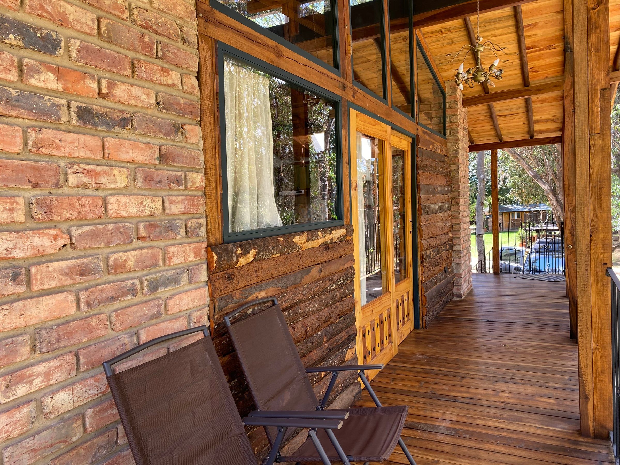 Corredor exterior con muro de ladrillo, carpintería de madera y piso de tablas