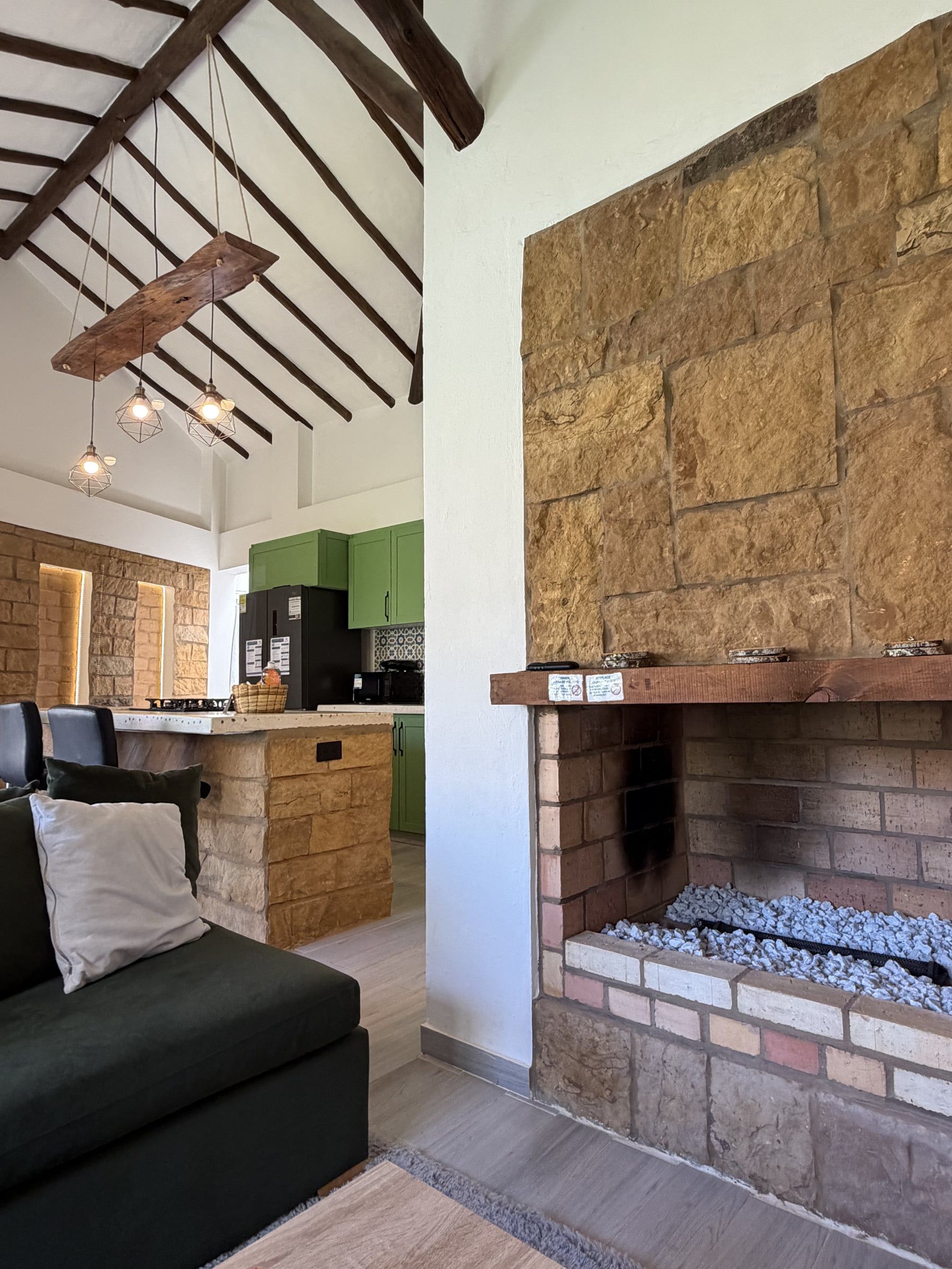 Chimenea de ladrillo con repisa de madera junto a un muro de piedra