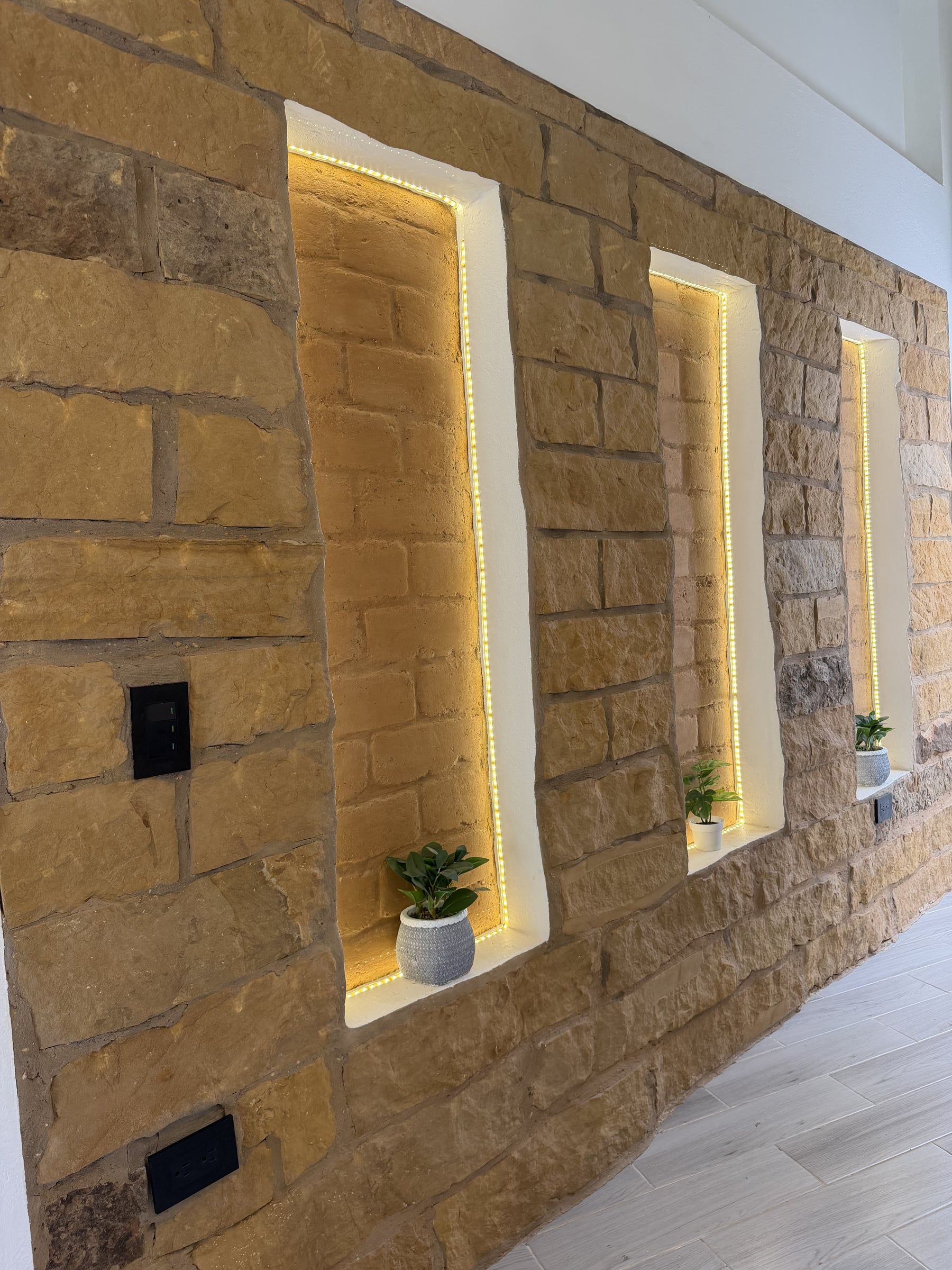 Muro de piedra con nichos verticales iluminados