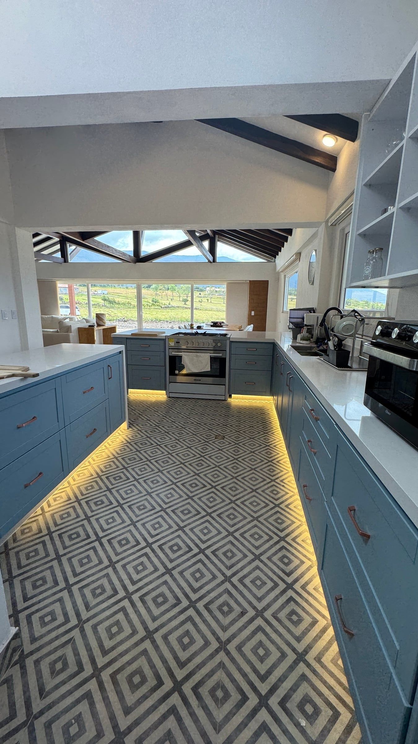 Cocina con muebles azules y piso de baldosa con patrón geométrico