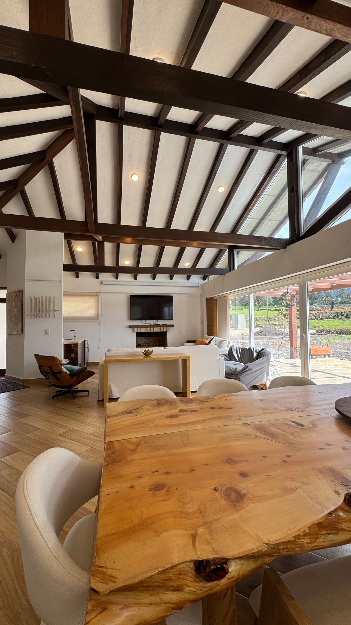Comedor de la Casa Mariva con mesa de madera maciza bajo las cerchas de madera de la cubierta