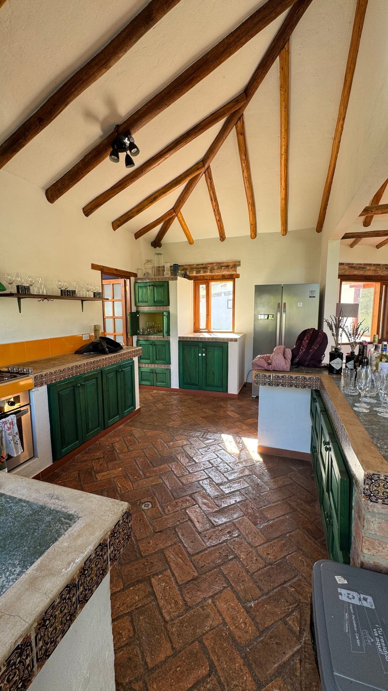 Casa Nido Verde antes de la remodelación: otra vista de la cocina con muebles verdes, nevera y piso de ladrillo