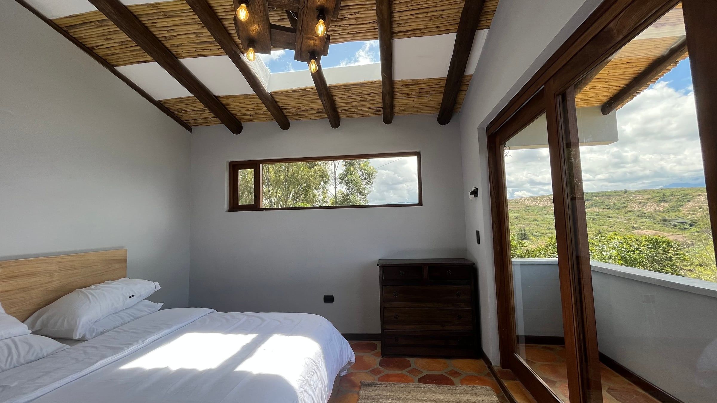 Habitación con cubierta de madera, ventana alta y ventanal lateral
